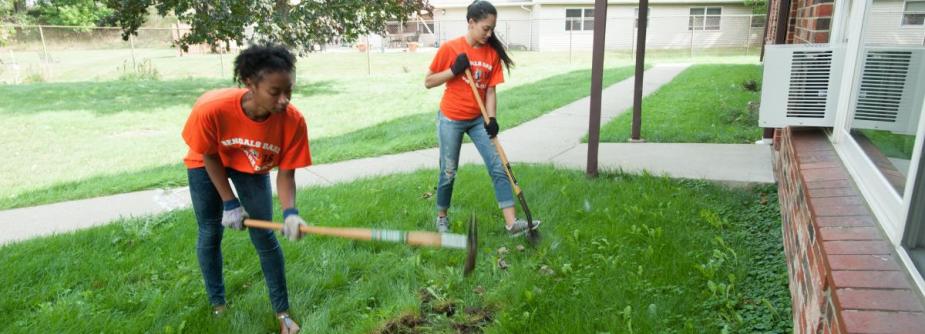 Two volunteer students working on a garden