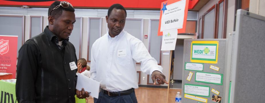Two men pointing to WEDI (Westminster Economic Development Initiative) tabling presentation.