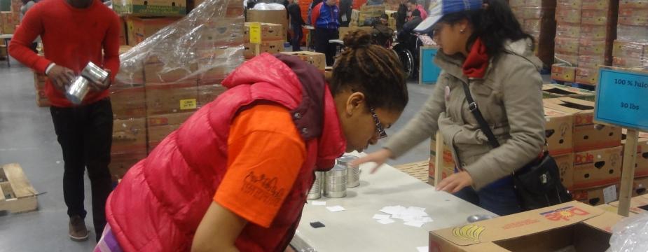 3 Buffalo state volunteers packing produce in boxes in a warehouse. 