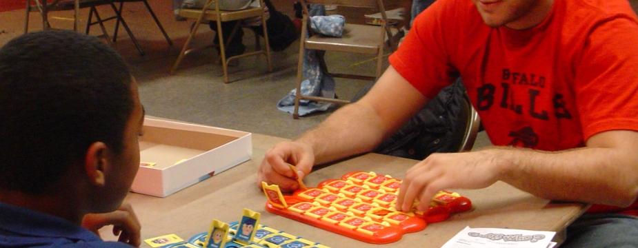 Adult and child playing Hasbro's "Guess Who?" game during game night. 
