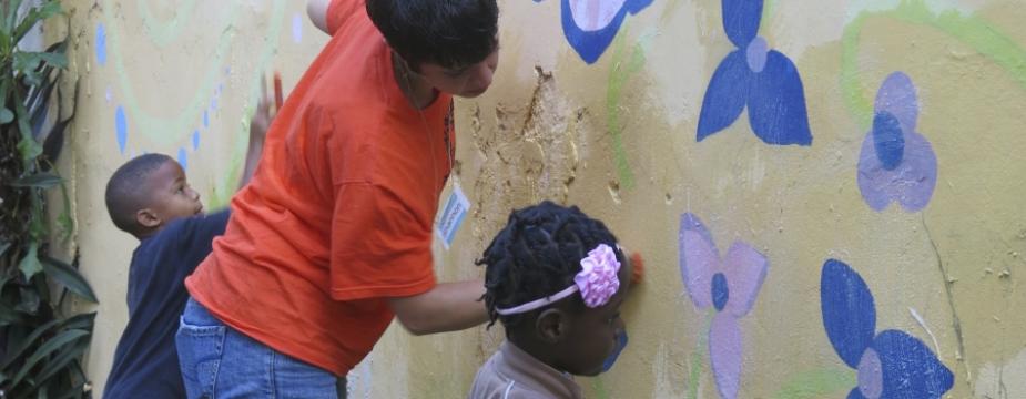 A woman and 2 kids scrub a wall 