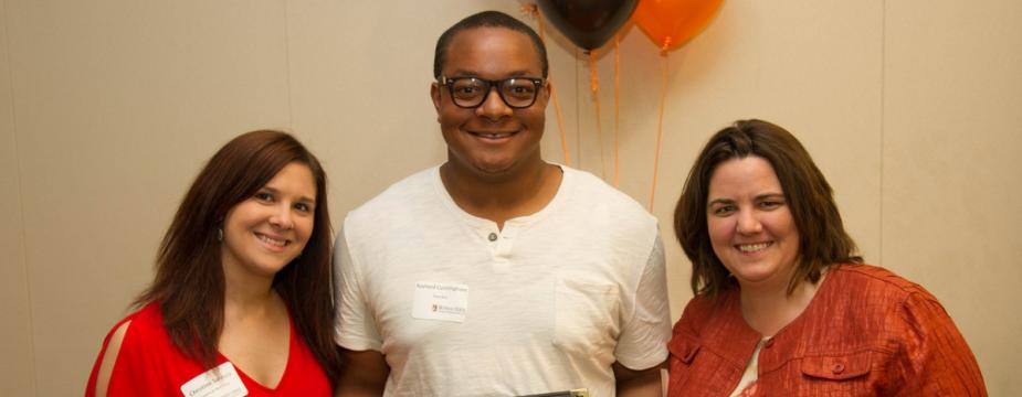 three individuals posing with a certificate